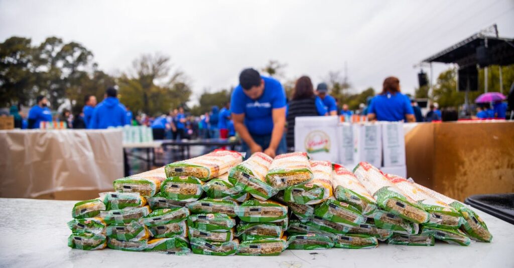 Volunteers distributing packaged food in an outdoor charity event.