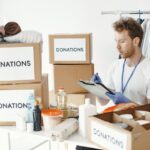 Home A man organizing donation boxes filled with clothes and food items at an NGO office.